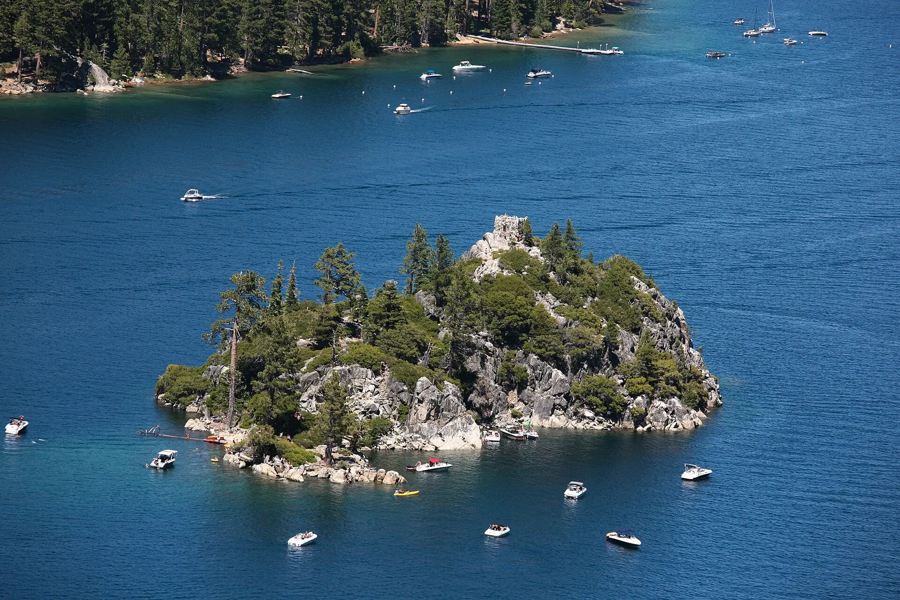 Fannette Island from above, its rocky summit with the ruined tea house, ringed by small boats on dark blue water